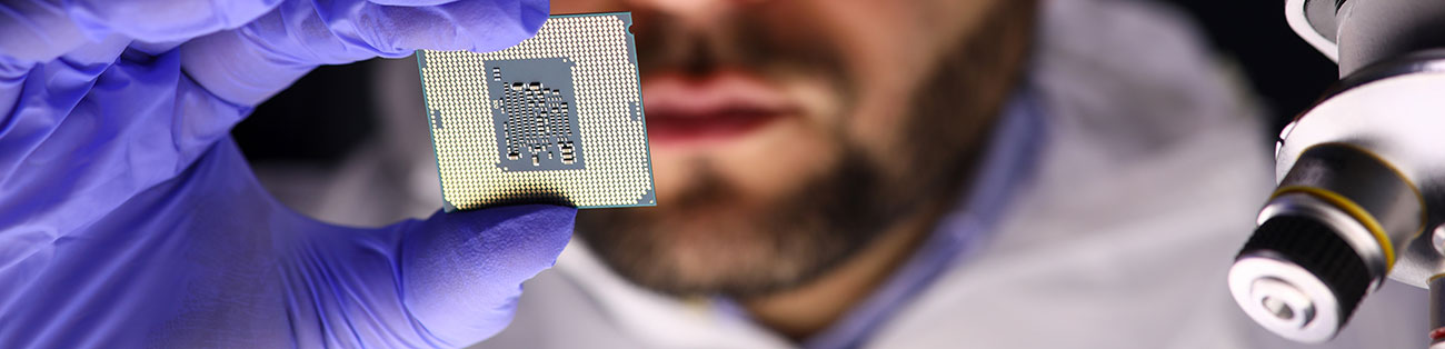 Closeup of a worker in a clean room holding a small circuit board